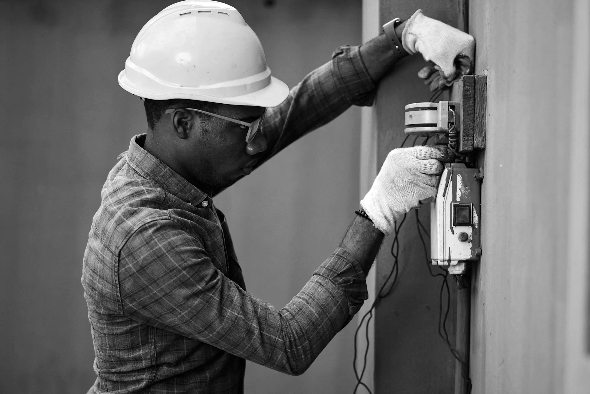 man in brown and white plaid dress shirt and yellow hard hat holding black and orange